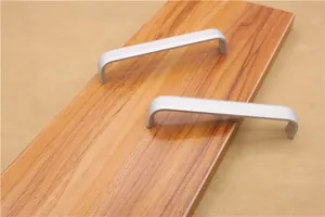 Close-up of two matte silver U-shaped aluminum cabinet handles on a wood surface