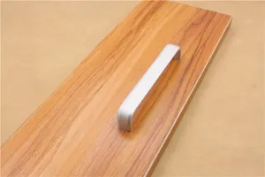Close-up of matte silver aluminum U-shaped furniture handle on wooden texture board