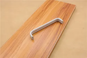 Detailed close-up of matte silver U-shaped aluminum cabinet handle on a wood surface