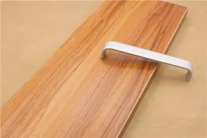 Detail shot of a matte silver U-shaped aluminum alloy handle on a light wood surface
