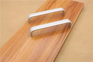 Close-up of matte silver aluminum U-shaped handles on a wooden cabinet drawer