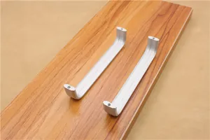 Macro detail of matte silver aluminum U-shaped furniture handles on a wooden board
