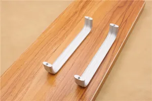 Detail of silver U-shaped aluminum cabinet handles with linear grooves and screw holes