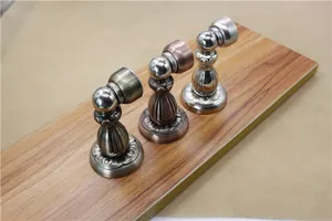 Detail of vintage magnetic door stoppers in bronze and chrome finishes on wood