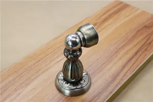 Detailed view of an antique bronze magnetic door stopper on a wooden surface