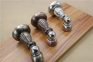 Three magnetic door stoppers in bronze, red copper, and silver finish on wood