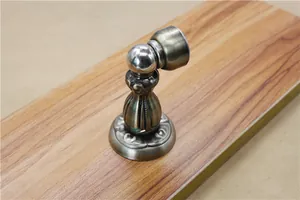 Detail of antique bronze magnetic door stopper with vintage pattern on wooden surface