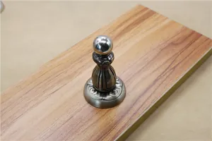 Detail of antique bronze magnetic door stopper with floral relief on a wooden surface