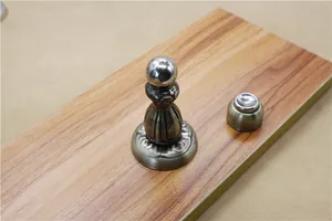 Detail of antique bronze magnetic door stopper with classical European relief on wood