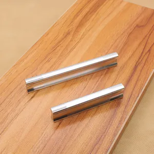 Close-up of solid silver aluminum drawer pulls with ergonomic curved grooves on wood