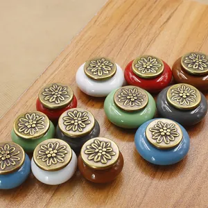 Colorful ceramic round cabinet knobs with antique floral metal caps on wood surface