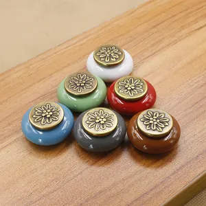 Detailed close-up of colorful ceramic cabinet knobs with floral engraved bronze caps