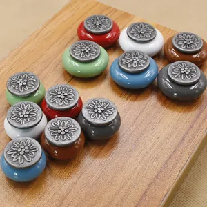 Detail of vintage round ceramic drawer knobs with antique silver floral zinc alloy tops