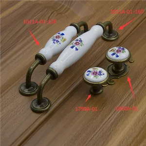 Floral ceramic cabinet handles with antique brass bases on dark wood background