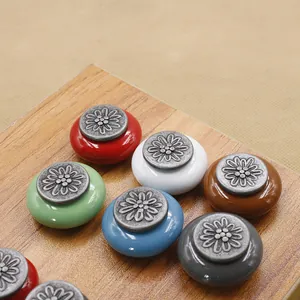 Detailed view of colorful ceramic drawer knobs with vintage floral alloy accents on wood