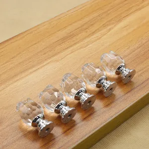 Detail of five 20mm clear crystal furniture knobs with silver metal bases on wood board