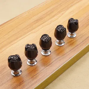 Set of five black rose cabinet knobs with silver metal bases on a wood surface