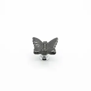 Glossy black butterfly ceramic drawer handle with polished silver base on white background