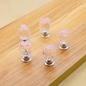 Macro detail of pink rose crystal glass knobs with silver bases on a wood surface