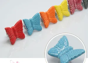 Macro detail of butterfly ceramic drawer knobs showing colorful glaze and embossed texture