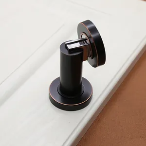 Detail of matte black magnetic door stopper with red copper edges on a white door