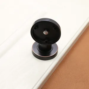Detail view of black matte magnetic door stopper with bronze finish and 3-hole base