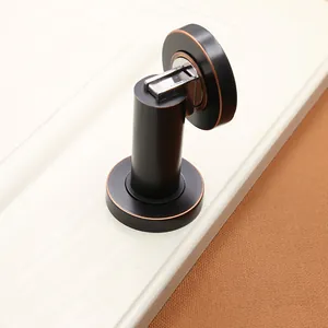Detail of matte black magnetic door stopper with vintage red copper edge on white door