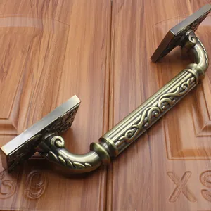 Detail of antique bronze door handle with floral relief on a wood background