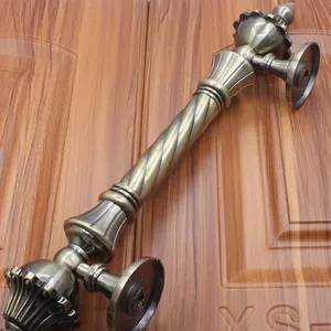 Detail of European antique bronze door handle with spiral twist grip on a wooden door