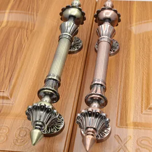Detail of antique bronze door handles with relief patterns on rustic wood grain