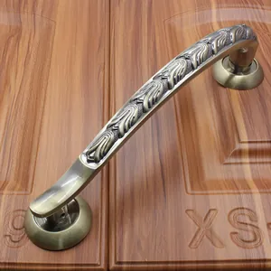 Detail of antique bronze door handle with embossed floral patterns on a wooden door