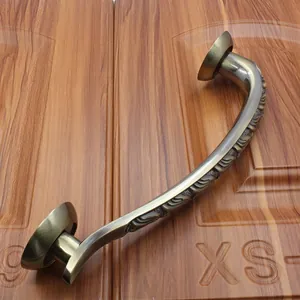 Detailed view of antique bronze door handle with ornate floral relief on wooden surface