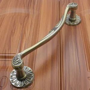 Detail of antique bronze door handle with sunburst engraving on dark wood background