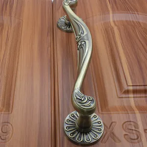 Detail of European antique bronze door handle with ornate floral relief on wood