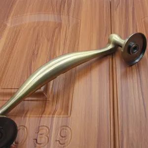 Detail of antique bronze curved door handle mounted on a dark wood grain panel