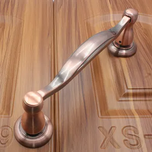 Close-up of European antique bronze door handle with brushed texture on wooden surface
