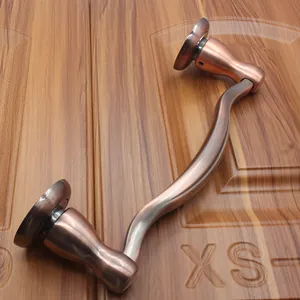 Detail of S-shaped antique bronze door handle with brushed metal finish on wood