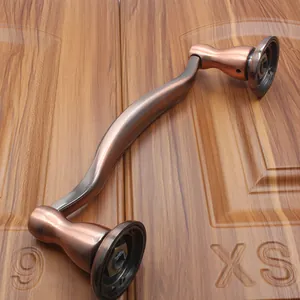 Close-up of S-shaped antique bronze door handle with brushed metal finish and round bases