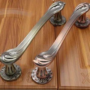 Detail of antique bronze door handles with intricate floral embossing on wooden background