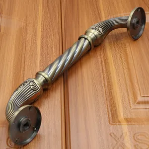 Detail of antique bronze door handle with spiral twist design on a wooden surface