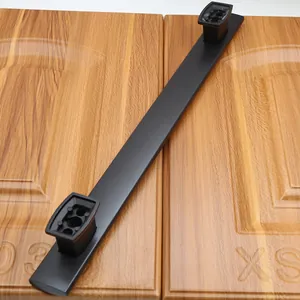 Close-up of matte black long cabinet handle handle on light brown wood door texture