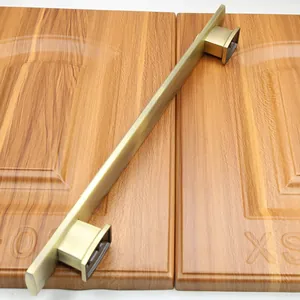 Detail of antique bronze long cabinet handle on textured wooden door panel