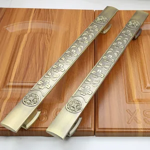 Detailed close-up of antique bronze door handles with ornate floral relief on wood panels
