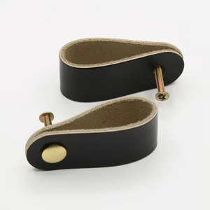 Detail view of black leather drawer pulls with gold mounting screws for modern furniture