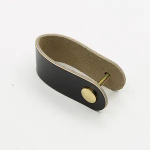 Detail of U-shaped black and brown leather drawer pull with golden brass screw fastener