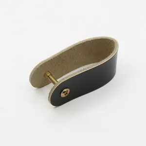Close-up of black leather U-shaped furniture pull with gold brass screw on white background