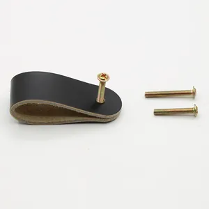 Detail view of black leather drawer handle set with brass screws on white background