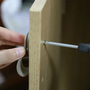 Detail of grey leather cabinet pull handle installed on wood with brass screw fastener