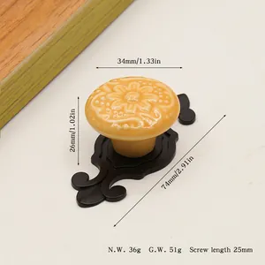 Detail of yellow ceramic cabinet knob with floral relief and black zinc alloy base