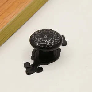Detailed view of a black vintage cabinet knob with floral relief and an elegant backplate